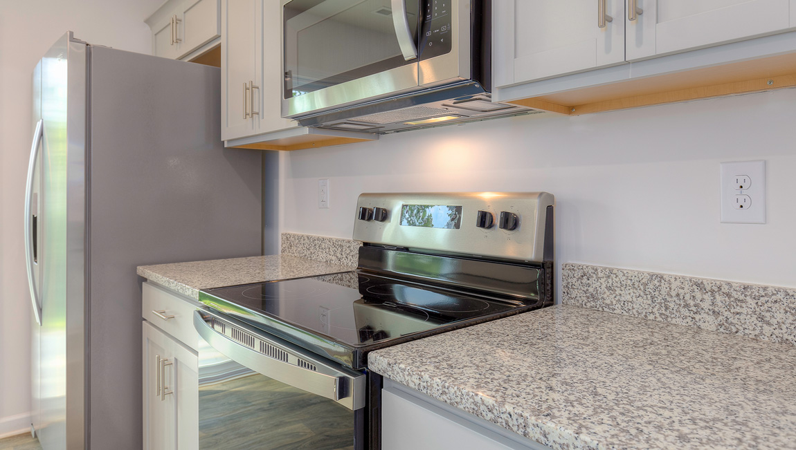 Kitchen with vinyl floors, granite counters, grey cabinets and stainless steel appliances