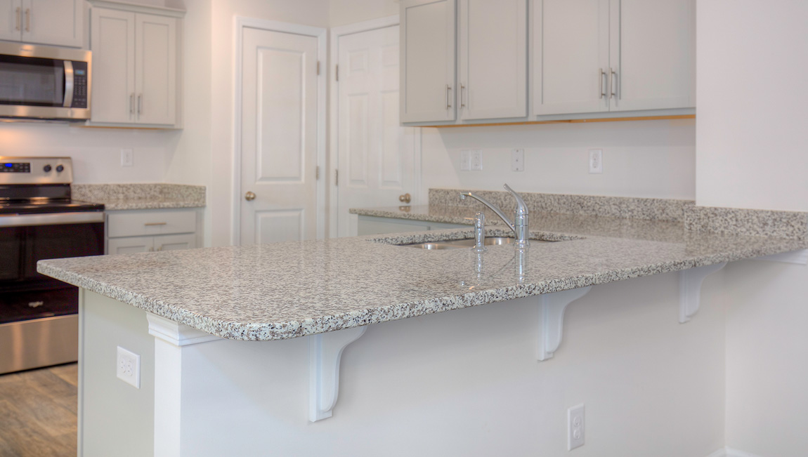 Kitchen with vinyl floors, granite counters, grey cabinets and stainless steel appliances