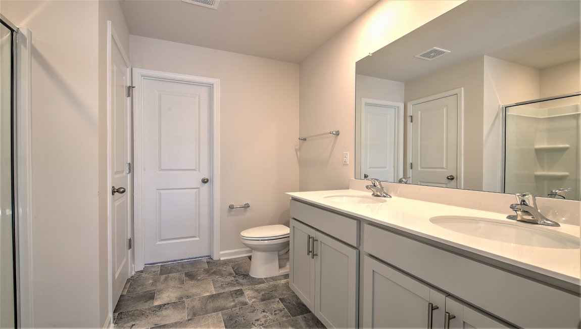 Primary bathroom with double sink vanity, and glass door shower