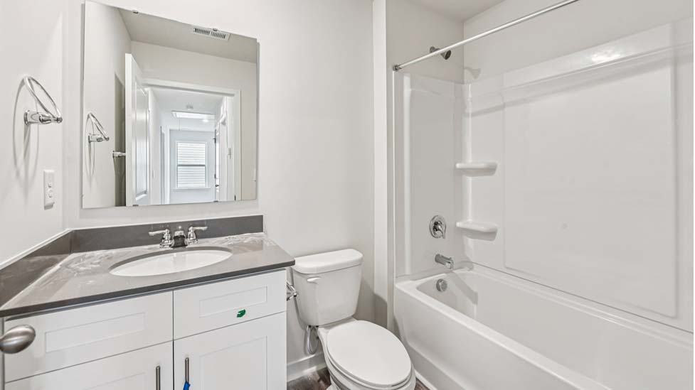 Bathroom with white counters and cabinets, and bathtub