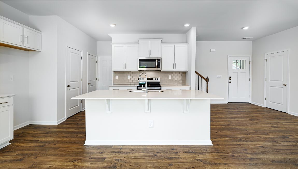 Kitchen and island, white cabinets, wood floors, and stainless steel appliances
