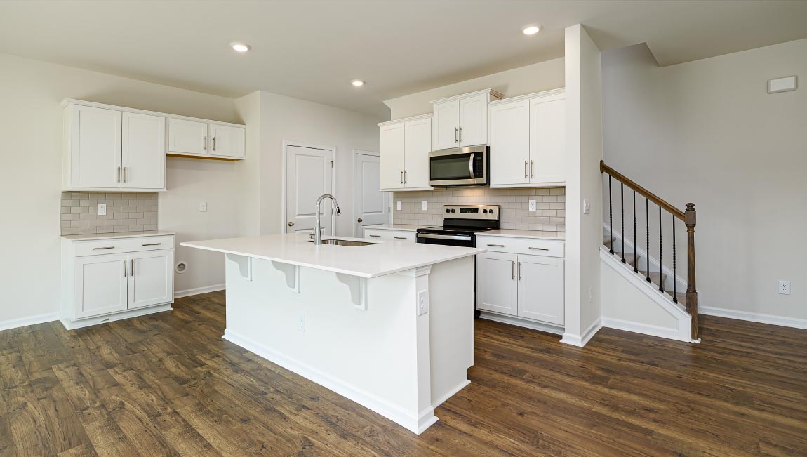 Kitchen and island, white cabinets, wood floors, and stainless steel appliances