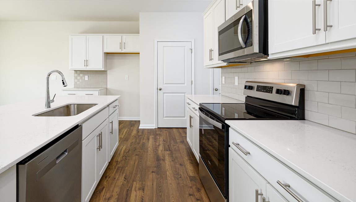 Kitchen and island, white cabinets, wood floors, and stainless steel appliances