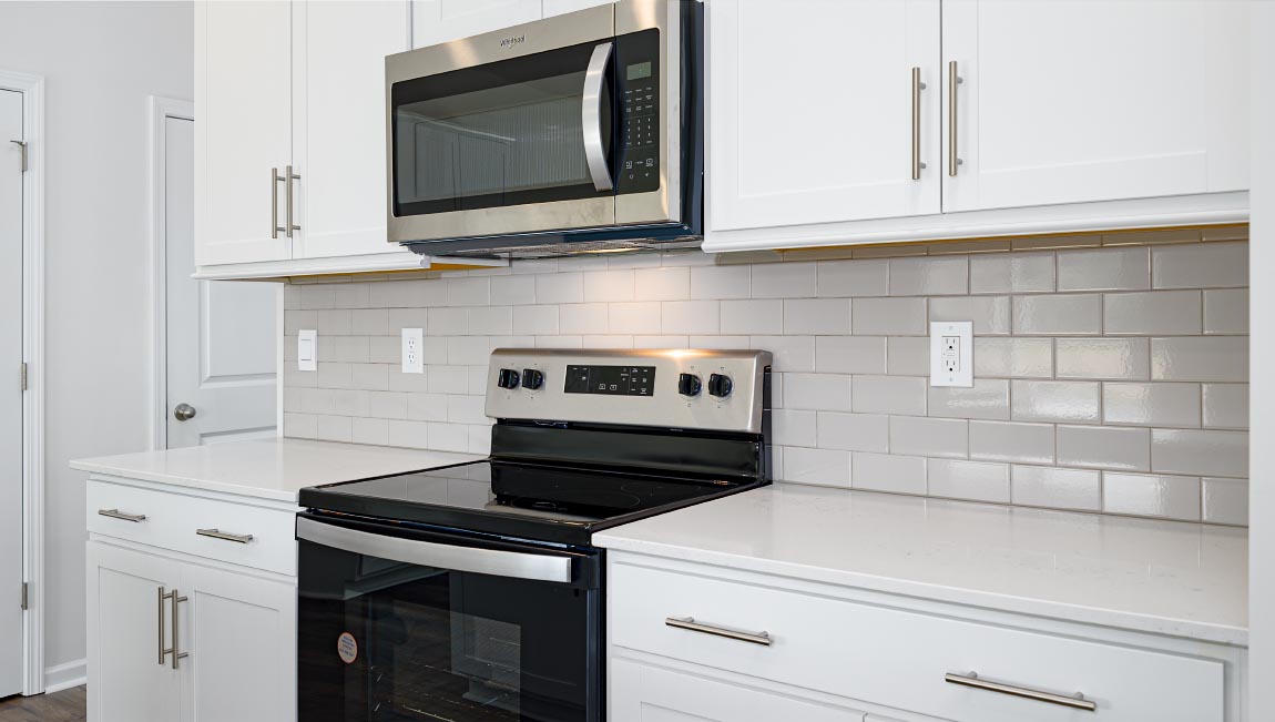 Kitchen and island, white cabinets, wood floors, and stainless steel appliances