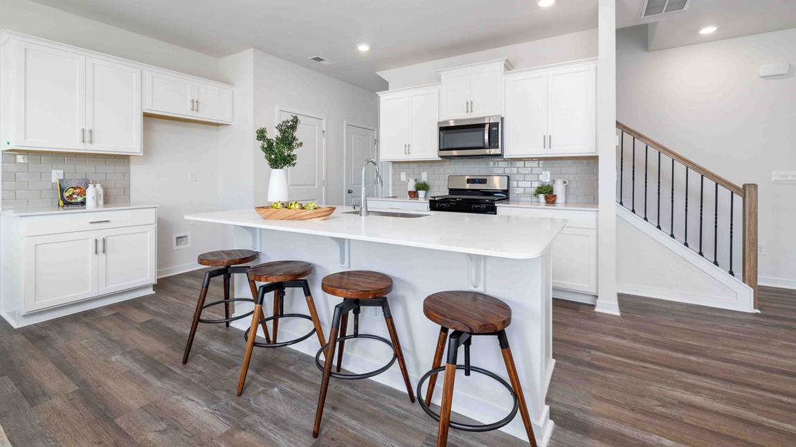 Kitchen and island, white cabinets, wood floors, and stainless steel appliances