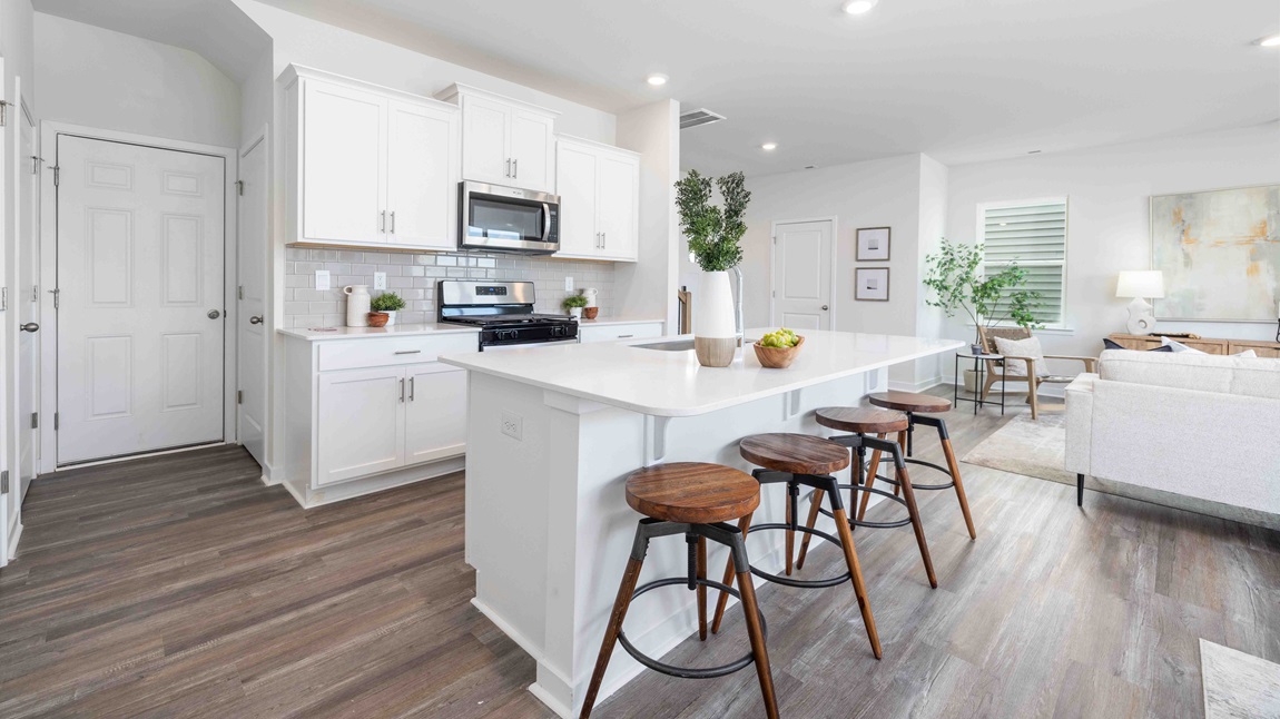 Kitchen and island, white cabinets, wood floors, and stainless steel appliances