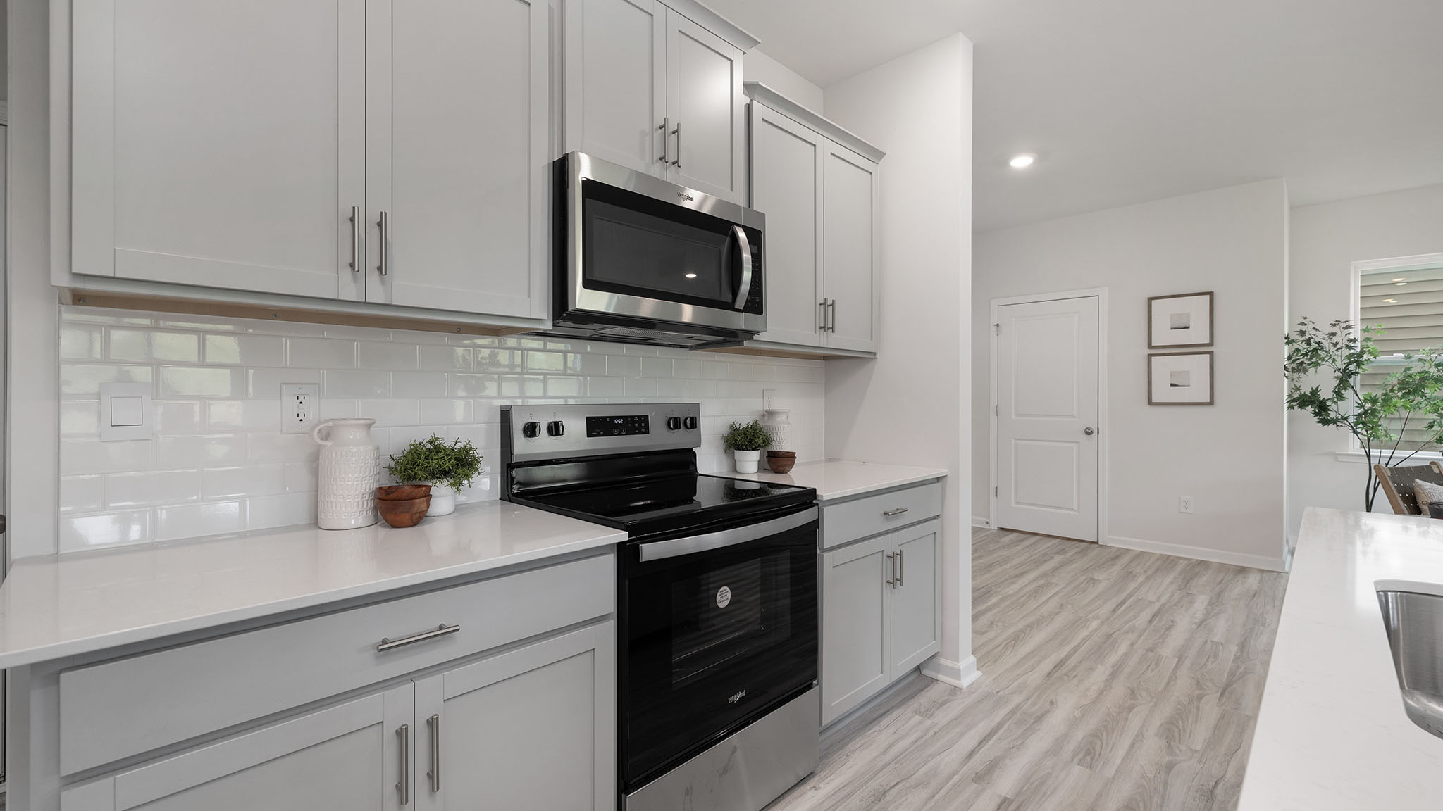 Kitchen and island, white cabinets, wood floors, and stainless steel appliances