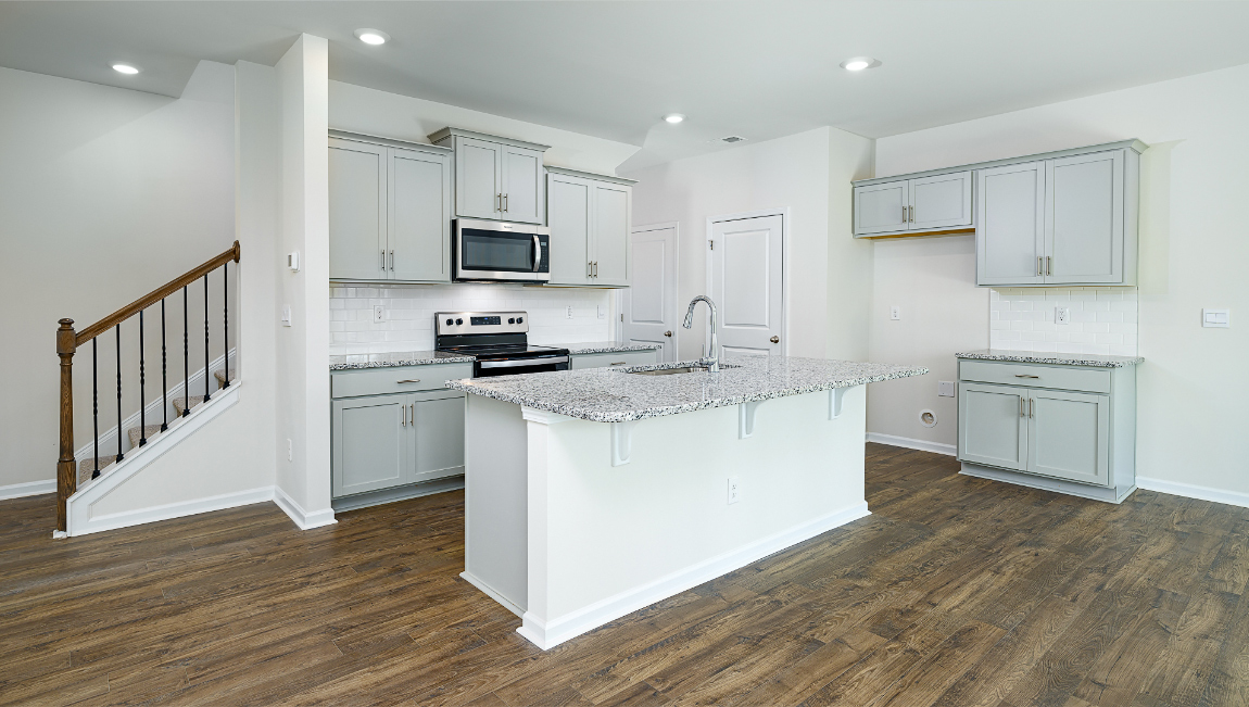 Kitchen and island, white cabinets, wood floors, and stainless steel appliances