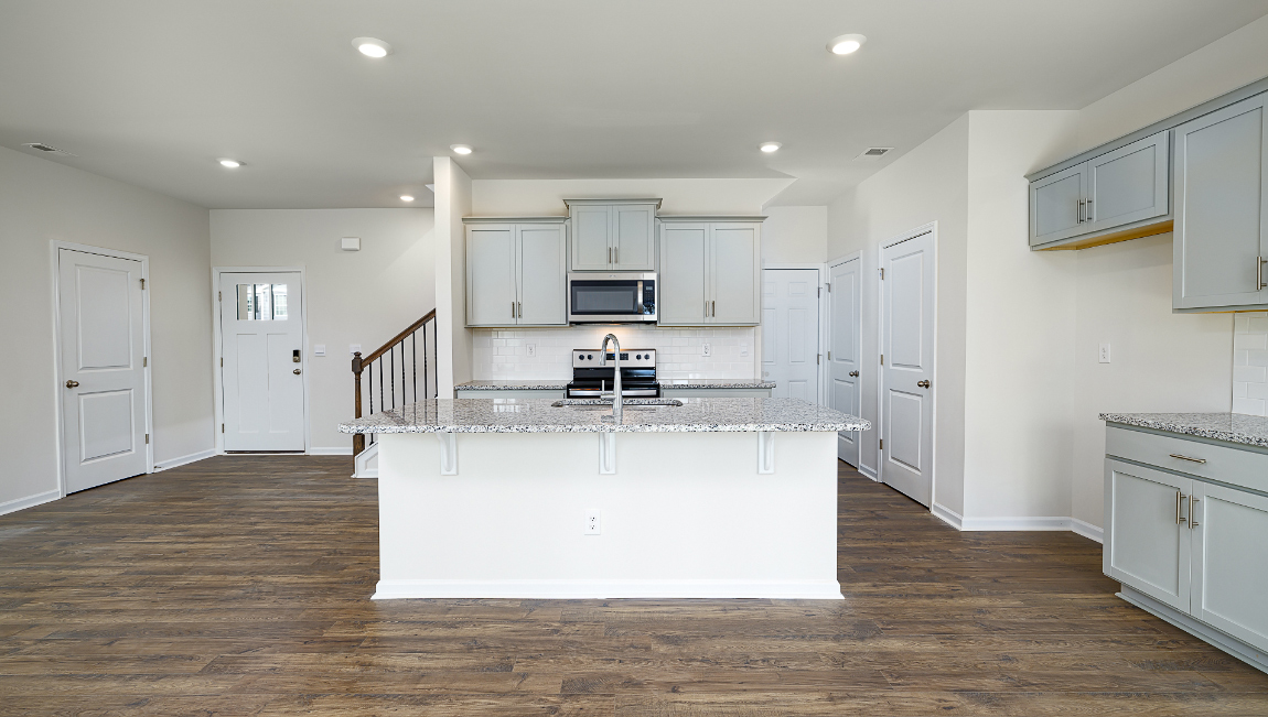 Kitchen and island, white cabinets, wood floors, and stainless steel appliances