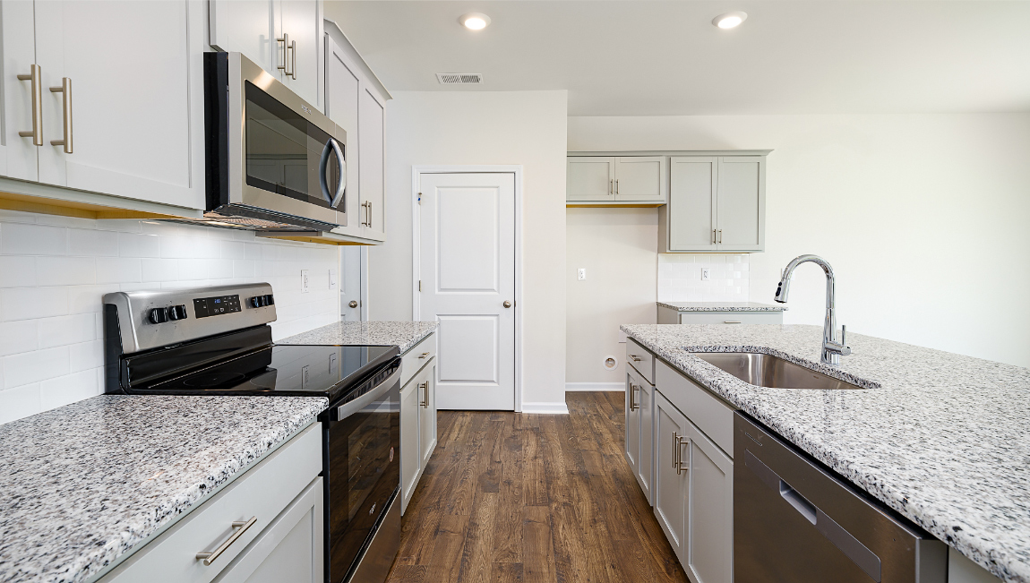 Kitchen and island, white cabinets, wood floors, and stainless steel appliances