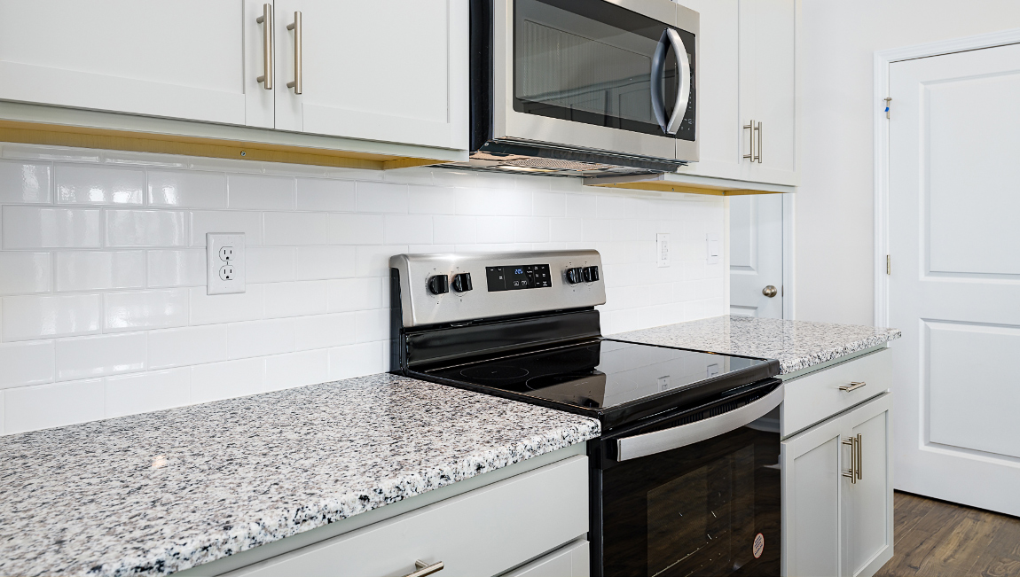Kitchen and island, white cabinets, wood floors, and stainless steel appliances
