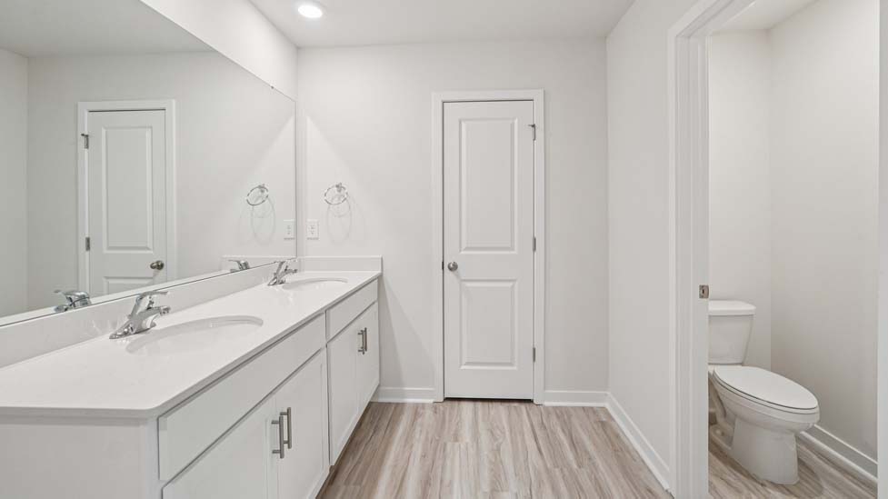 Primary bathroom with double sinks, white cabinets and glass door shower