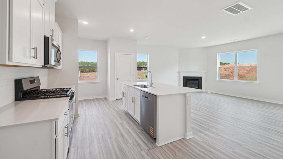 Kitchen and island with white cabinets, white subway tile backsplash and stainless steel appliances