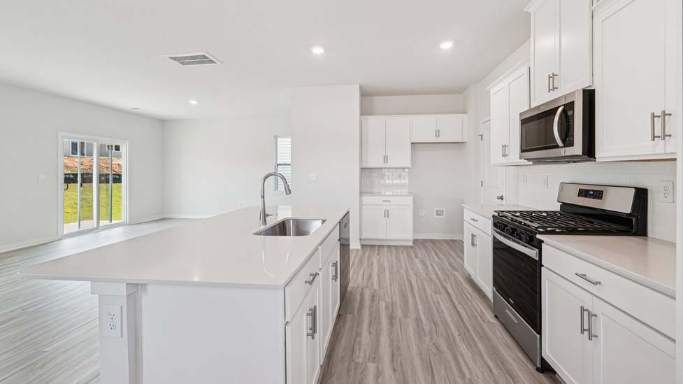 Kitchen and island with white cabinets, white subway tile backsplash and stainless steel appliances
