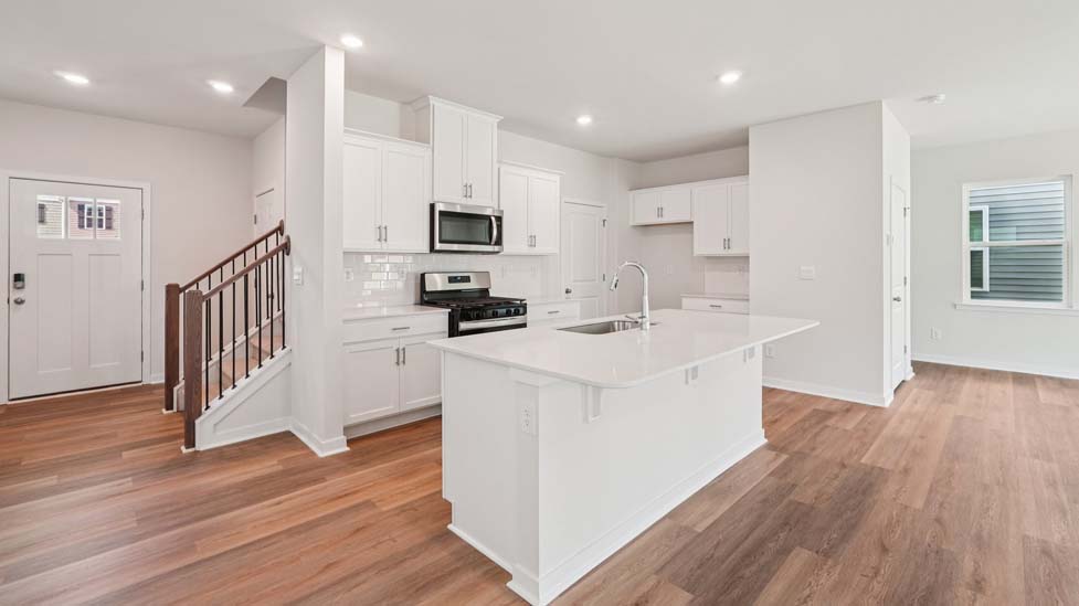 Kitchen and island with white cabinets, white subway tile backsplash and stainless steel appliances