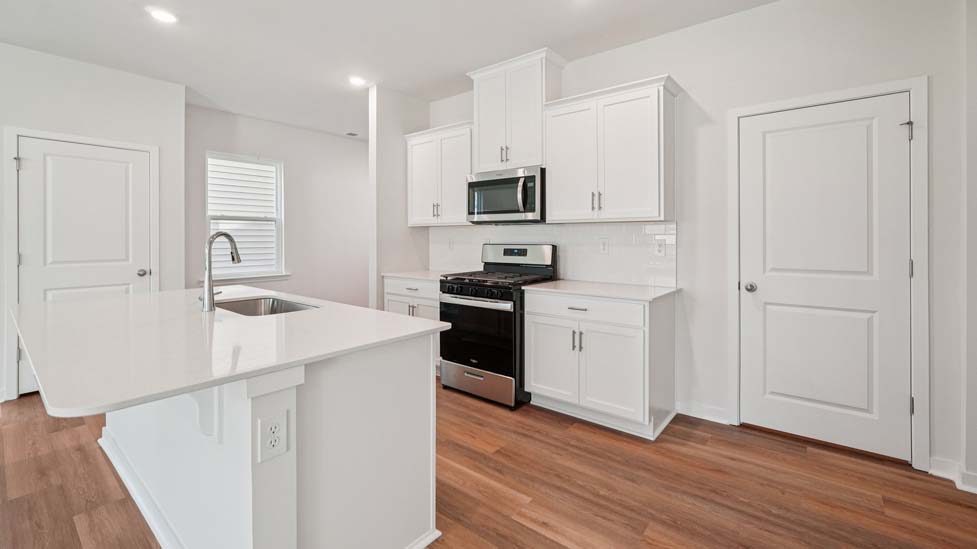 Kitchen and island with white cabinets, white subway tile backsplash and stainless steel appliances