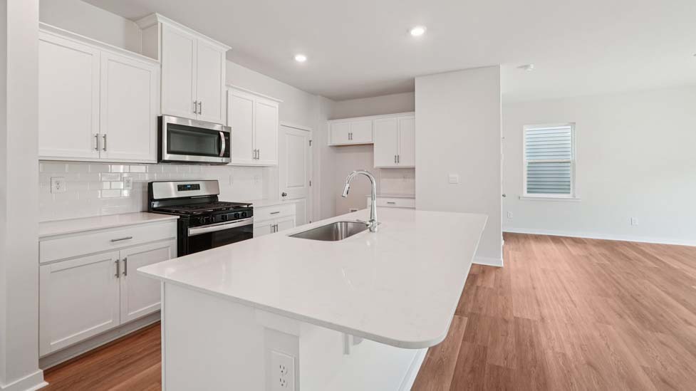 Kitchen and island with white cabinets, white subway tile backsplash and stainless steel appliances