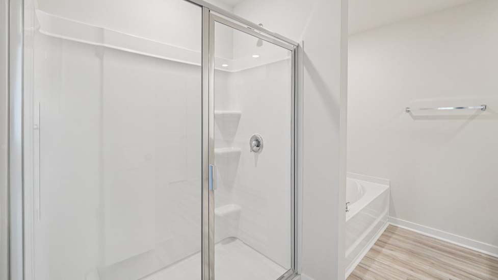 Primary bathroom with double sinks, white cabinets and glass door shower