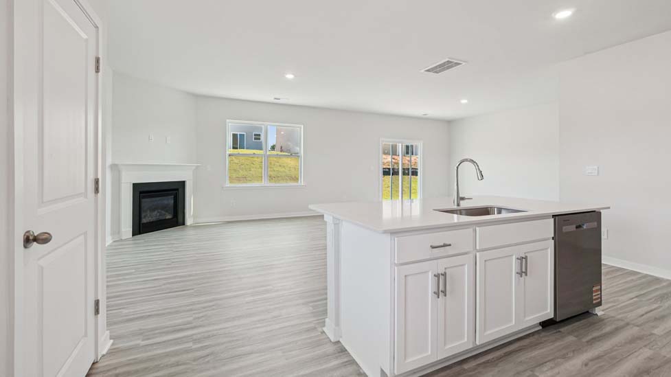Kitchen and island with white cabinets, white subway tile backsplash and stainless steel appliances