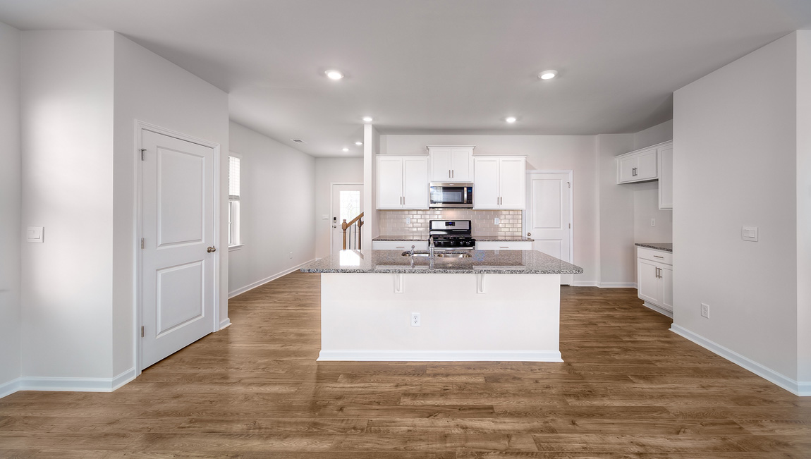 Kitchen and island with white cabinets, white subway tile backsplash and stainless steel appliances