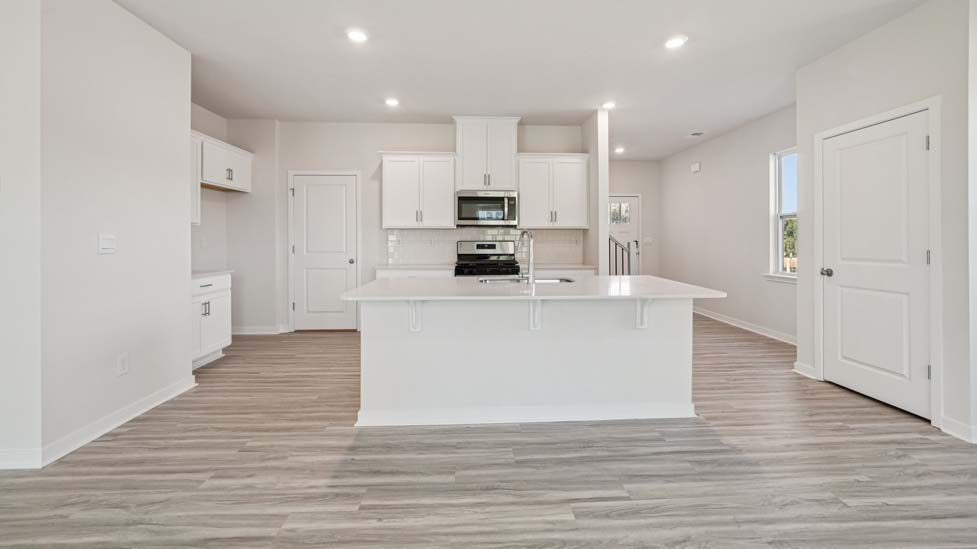 Kitchen and island with white cabinets, white subway tile backsplash and stainless steel appliances
