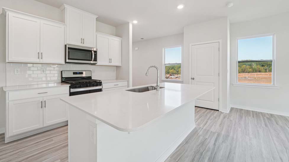 Kitchen and island with white cabinets, white subway tile backsplash and stainless steel appliances
