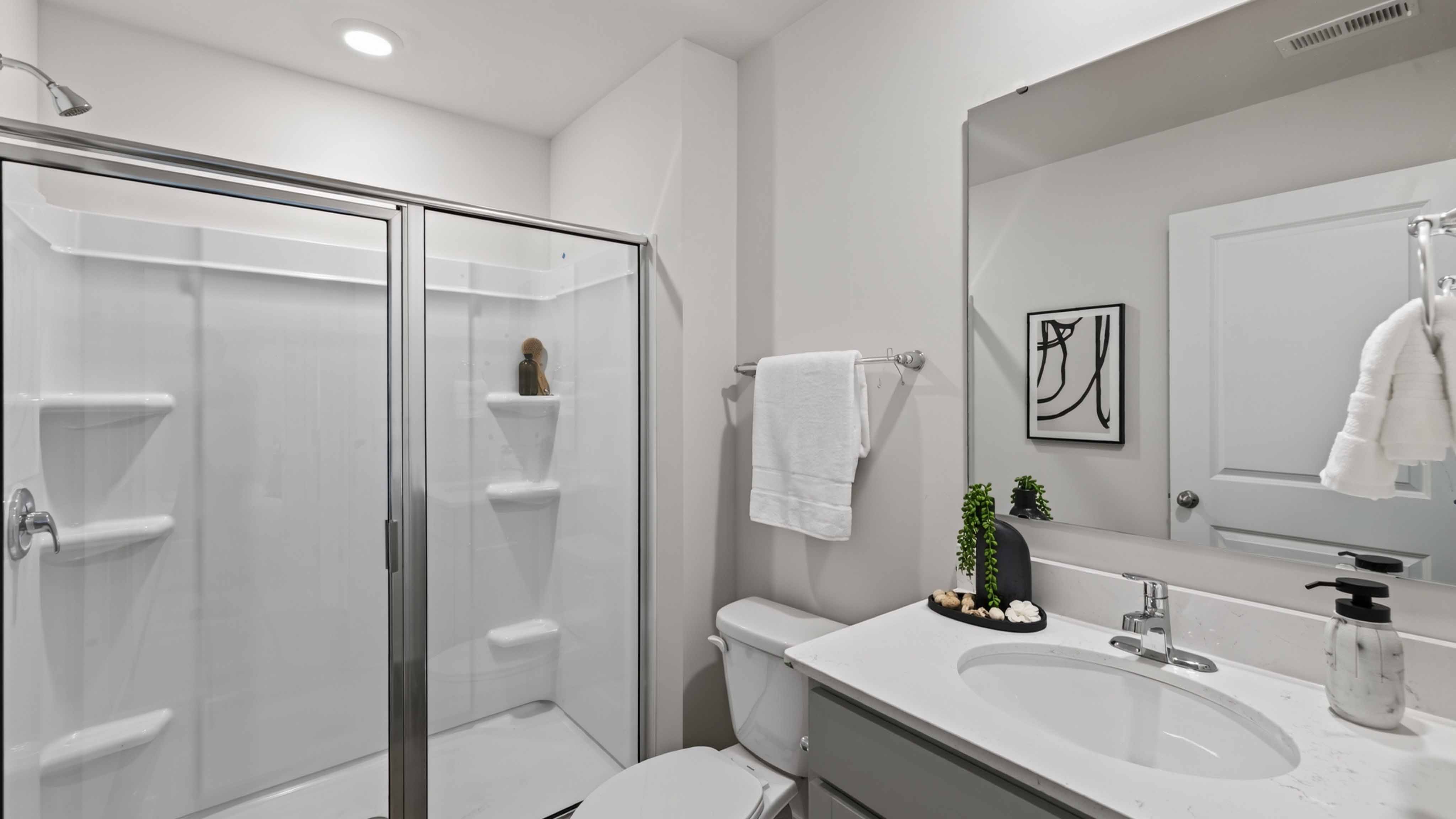 Bathroom with standing shower, white counter and cabinets
