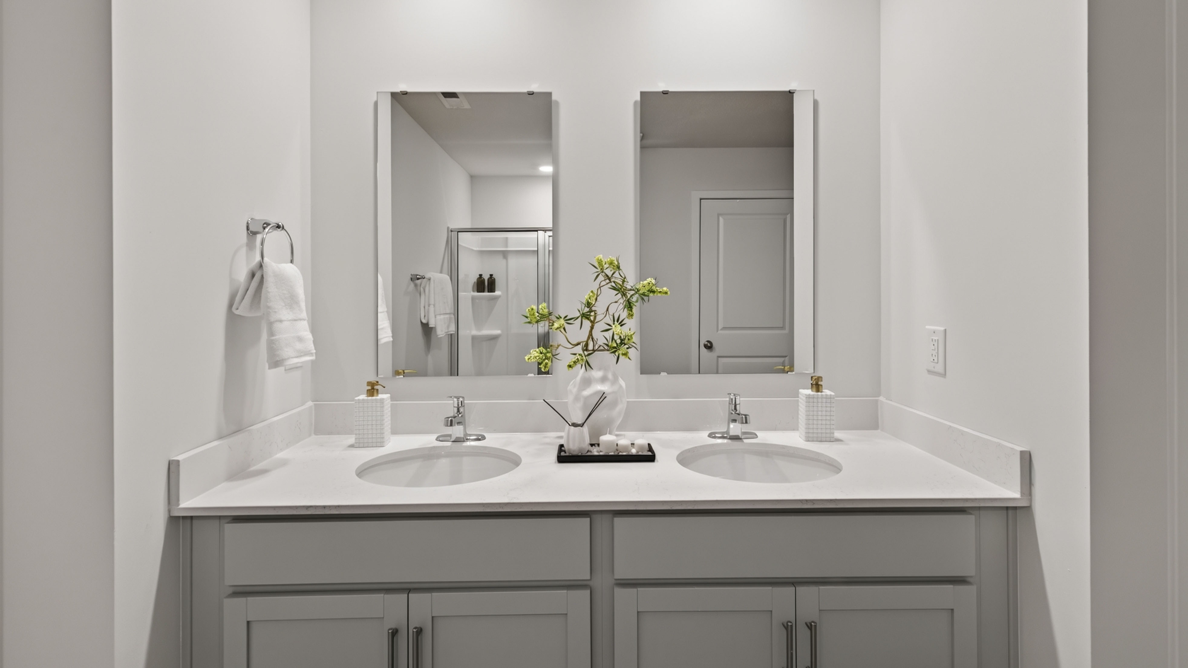 Primary bathroom with double sinks, white cabinets and counters