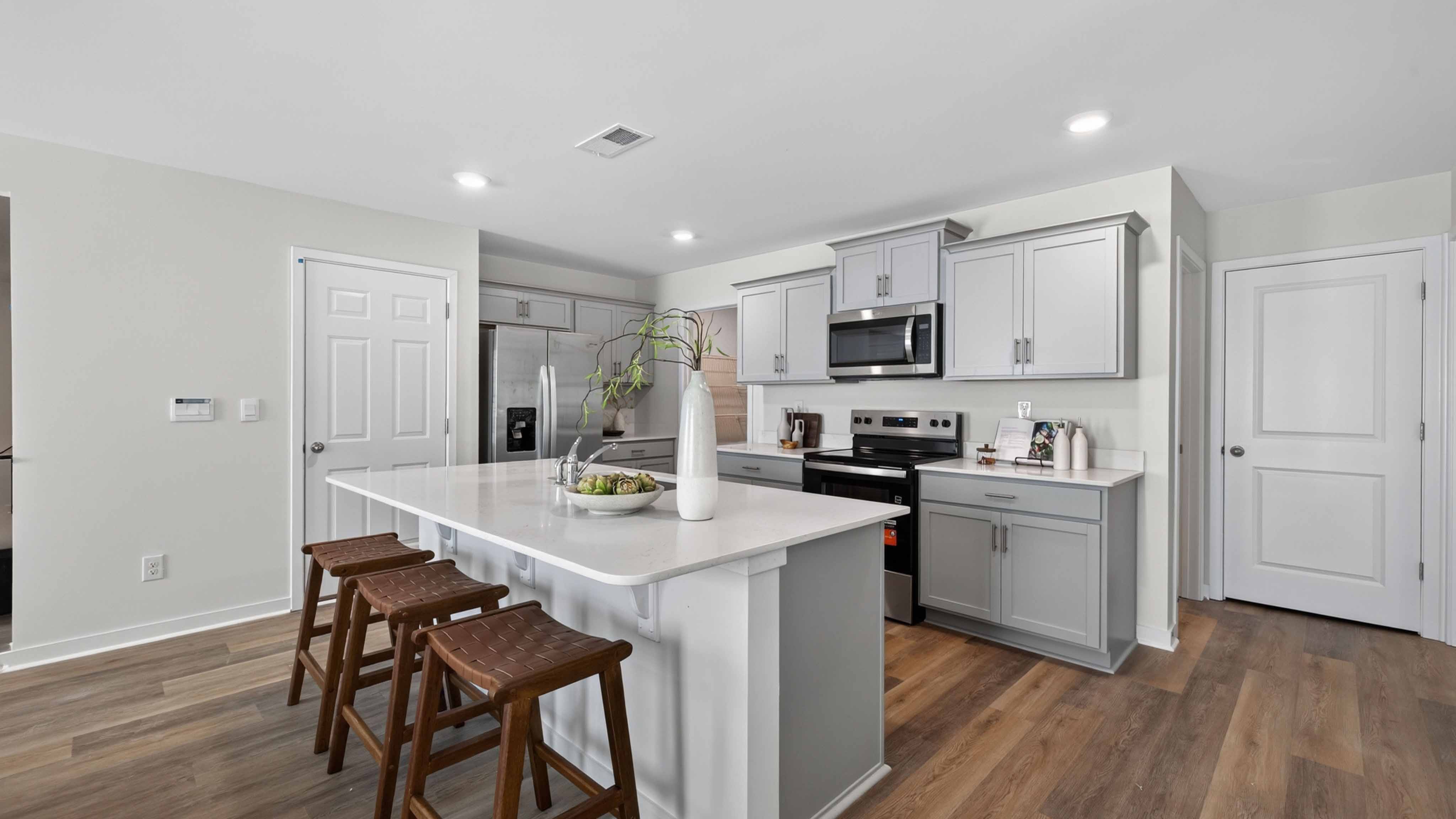 Kitchen and island with white cabinets, subway tile backsplash, and stainless steel appliances
