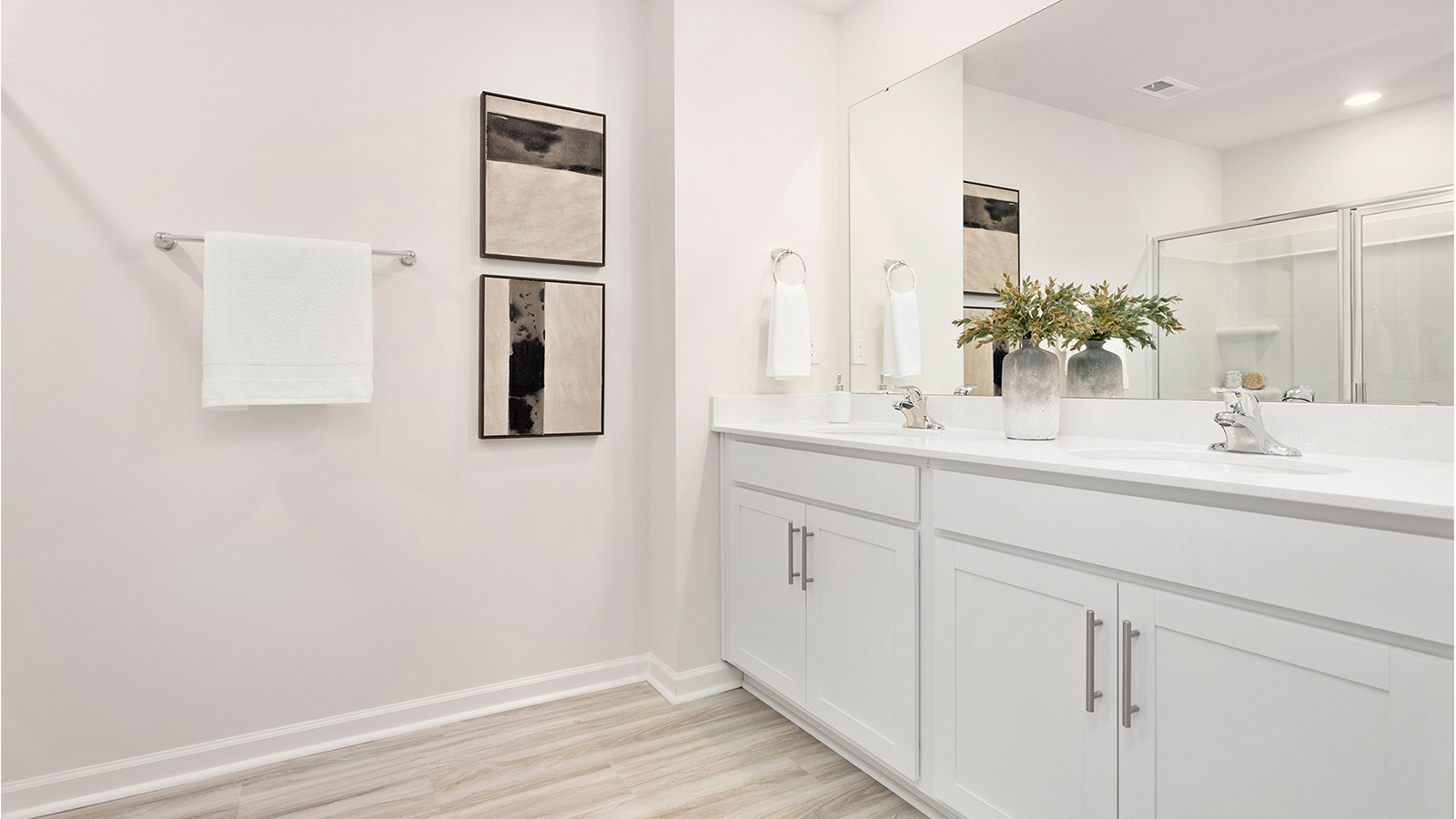 Primary bathroom with double sinks, white cabinets and counters