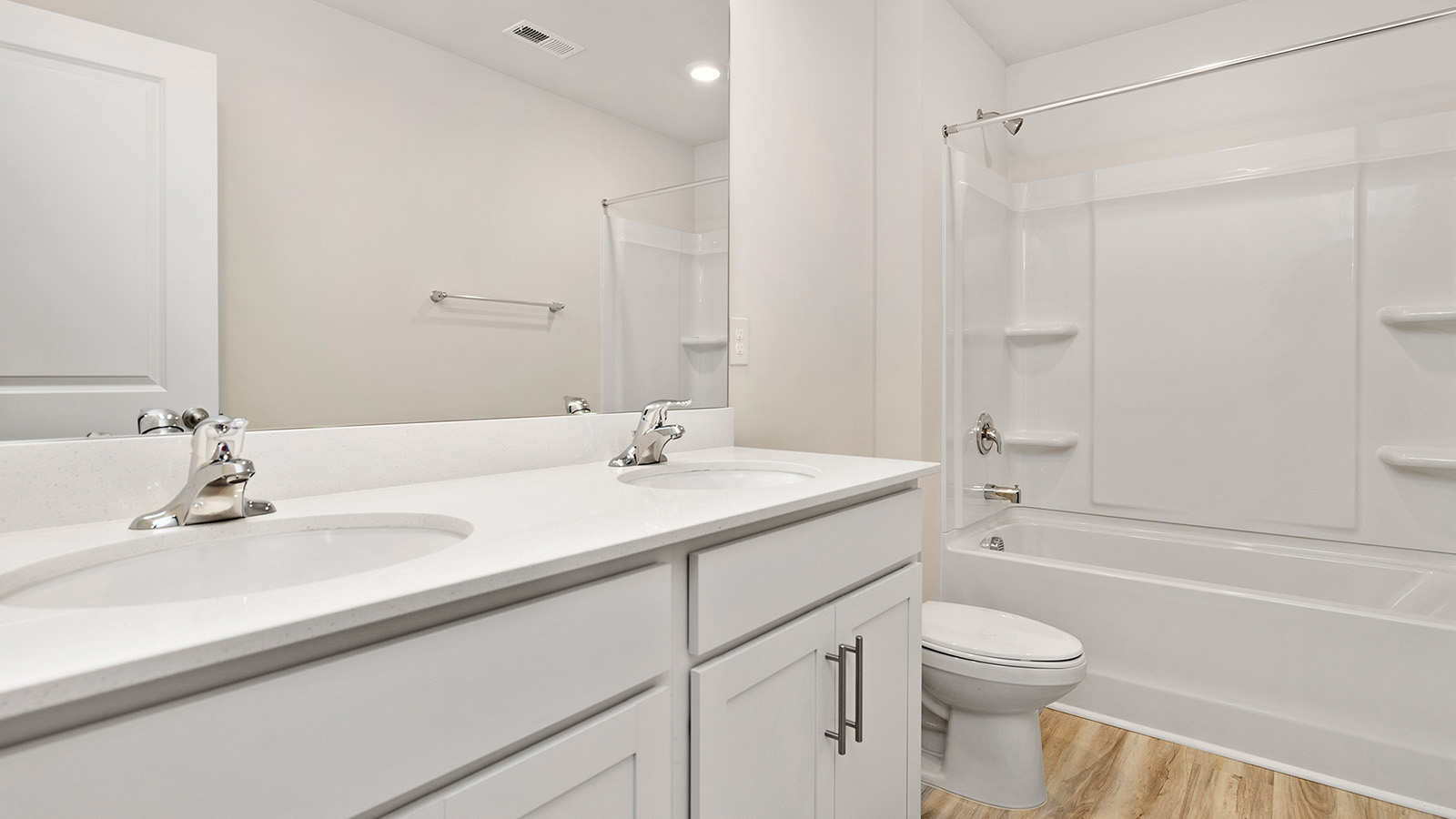 Bathroom with bathtub, double sinks, and white counters and cabinets
