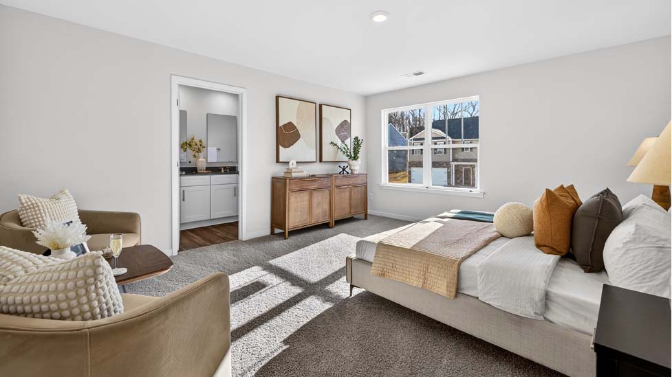 Primary carpeted bedroom with large window, view of bathroom door