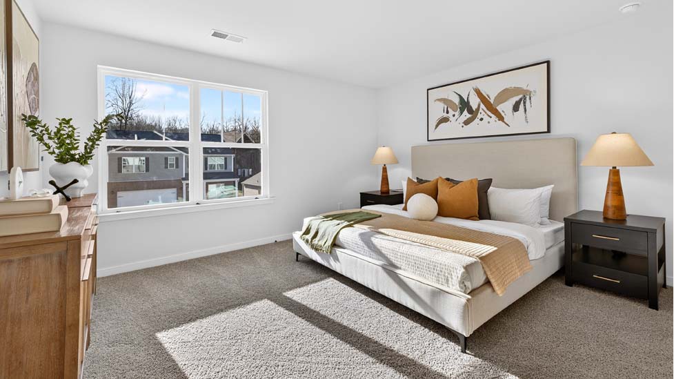 Primary carpeted bedroom with large window, view of bathroom door