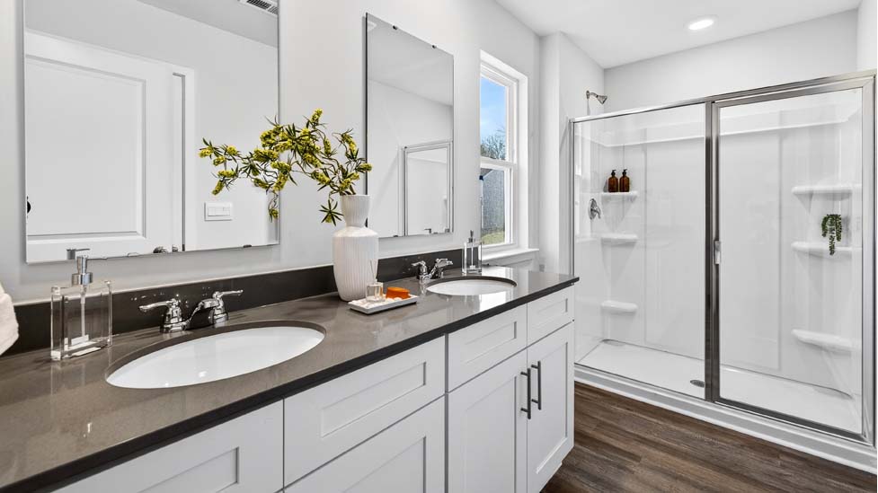 Bathroom with white counters and cabinets, and glass door standing shower