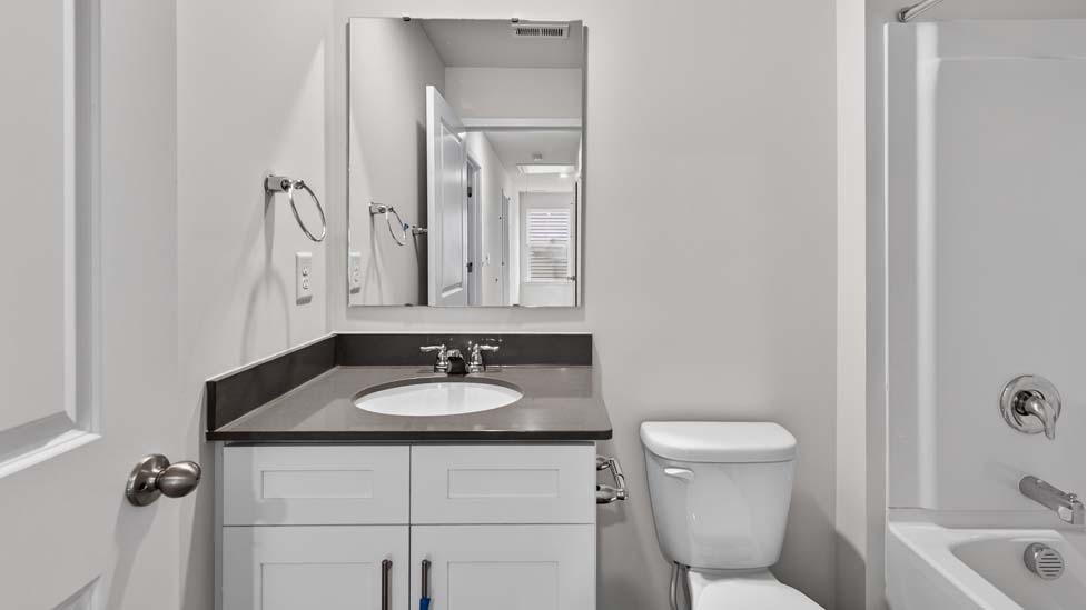 Bathroom with white counters and cabinets, and bathtub