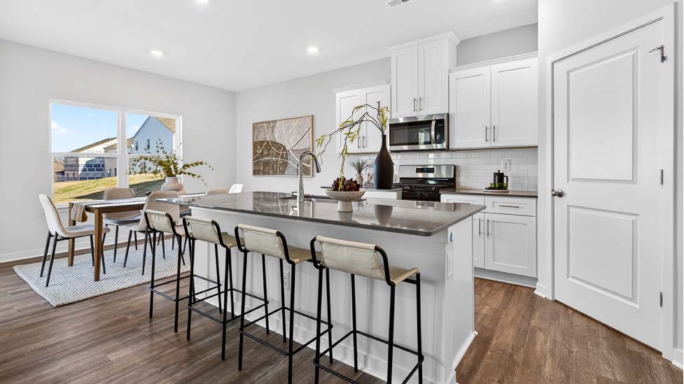 Kitchen and island with white cabinets, quartz counters, wood floors and stainless steel appliances