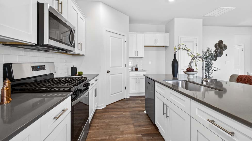 Kitchen and island with white cabinets, quartz counters, wood floors and stainless steel appliances