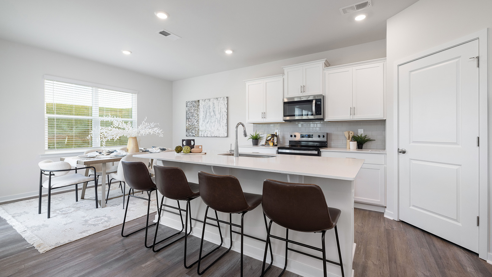 Kitchen and island with white cabinets, quartz counters, wood floors and stainless steel appliances