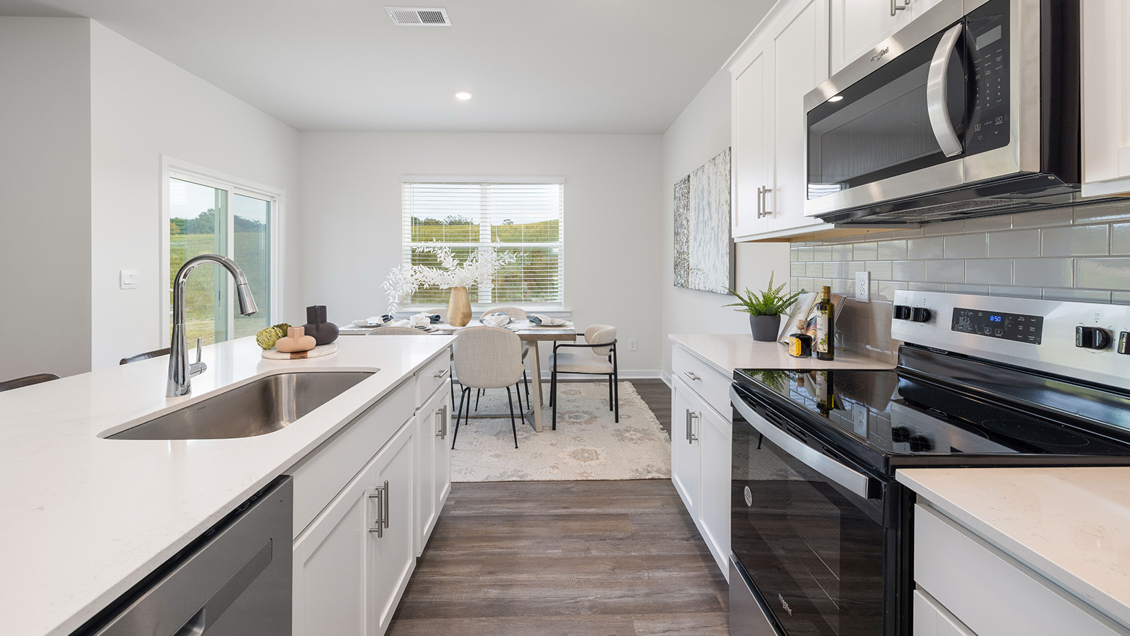 Kitchen and island with white cabinets, quartz counters, wood floors and stainless steel appliances