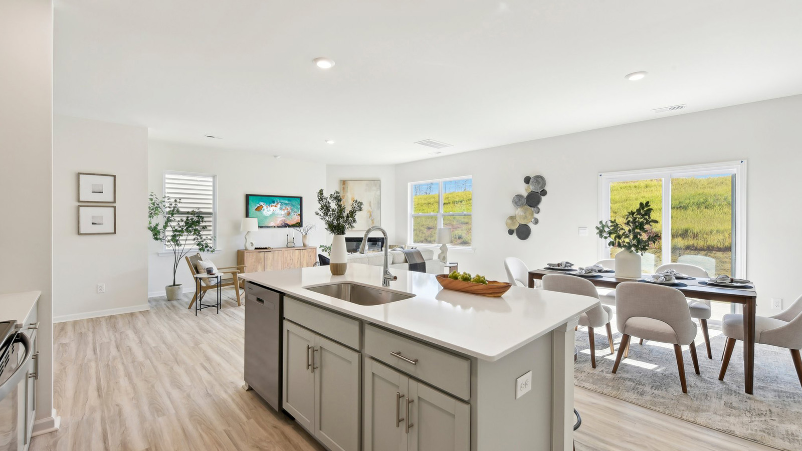 Kitchen and island, white cabinets, wood floors, and stainless steel appliances