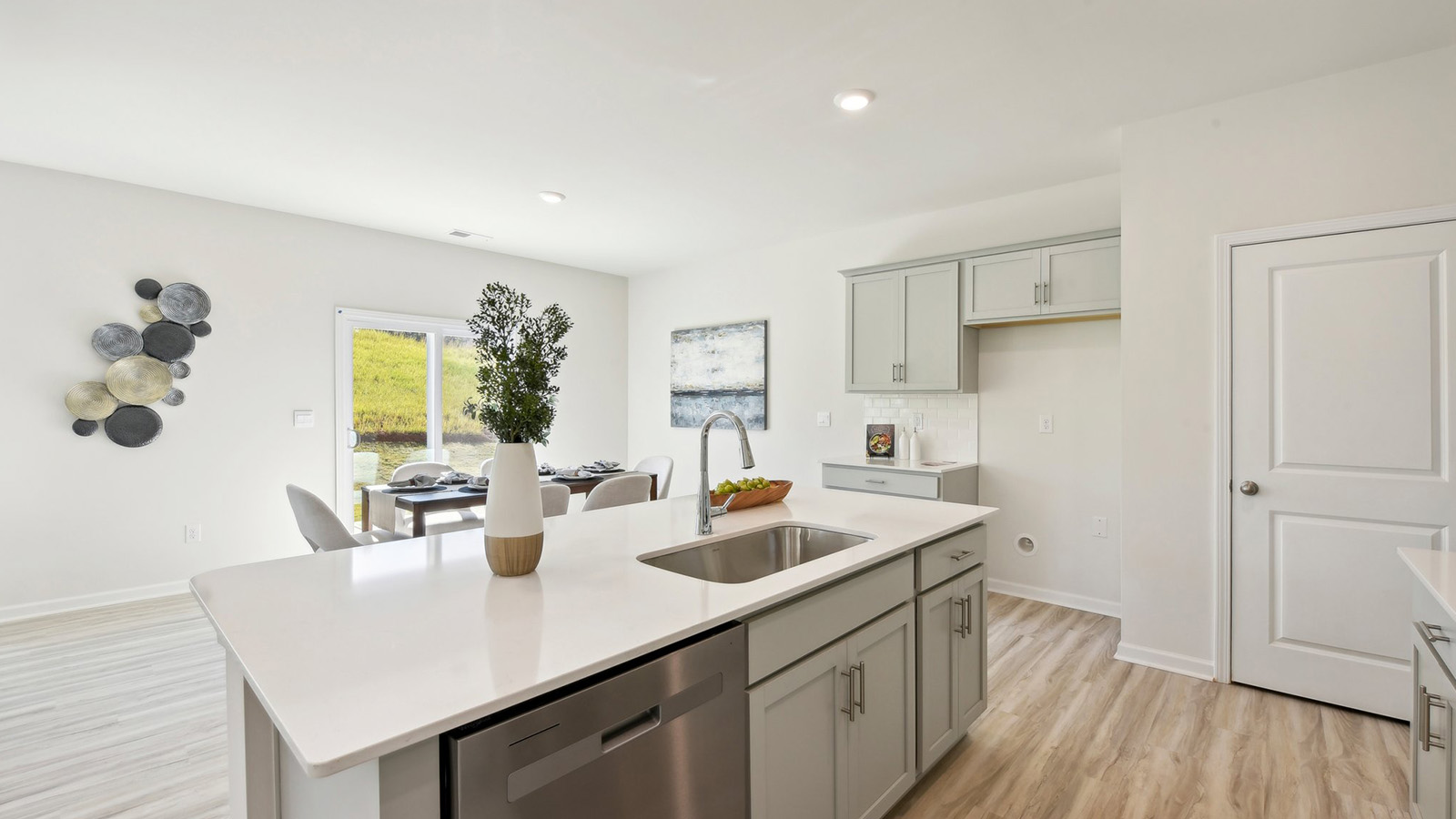 Kitchen and island, white cabinets, wood floors, and stainless steel appliances