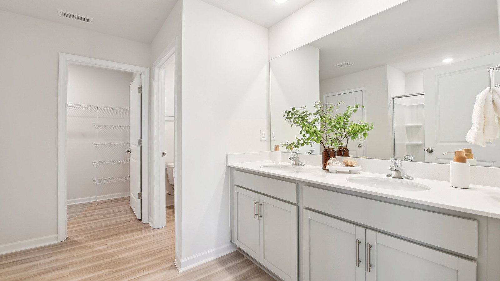 Primary bathroom with double sinks, white cabinets and counters