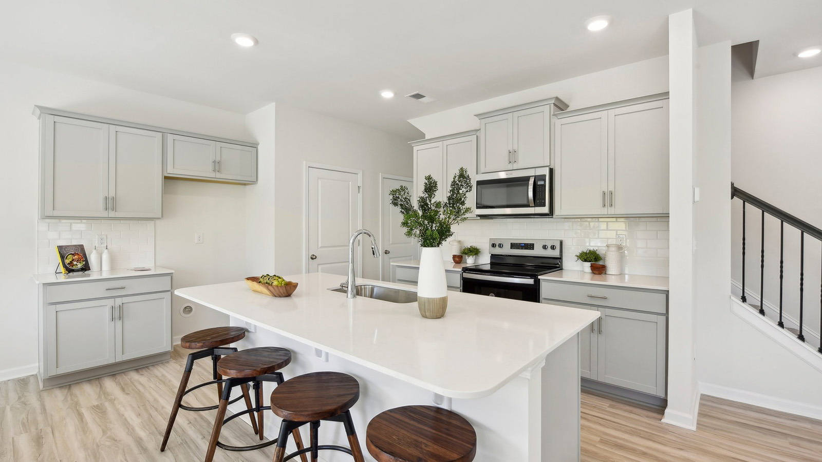 Kitchen and island, white cabinets, wood floors, and stainless steel appliances
