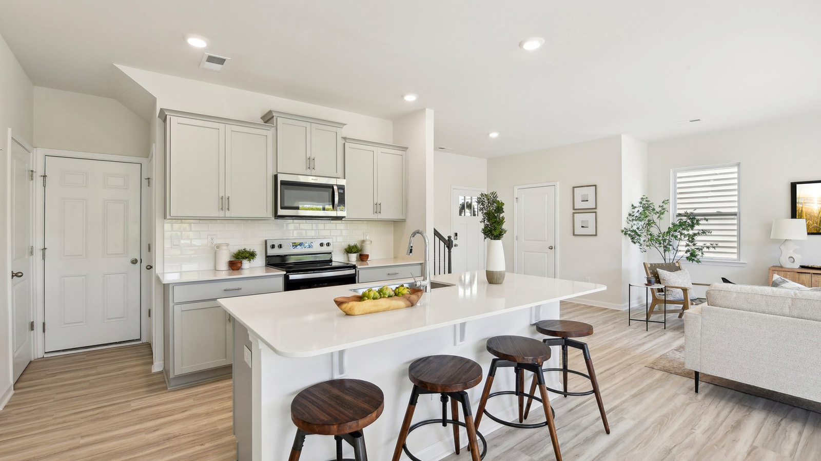 Kitchen and island, white cabinets, wood floors, and stainless steel appliances