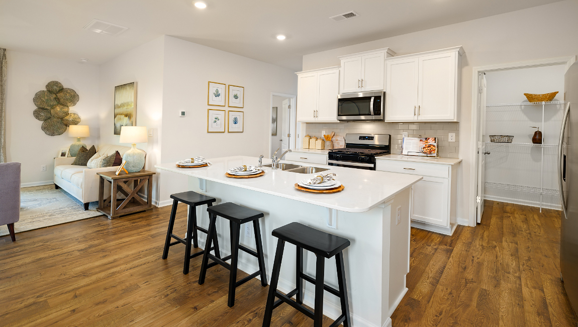 Kitchen and island with white cabinets, subway tile backsplash, and stainless steel appliances