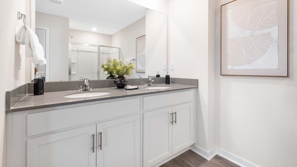 Primary bathroom with double sinks, white cabinets and counters