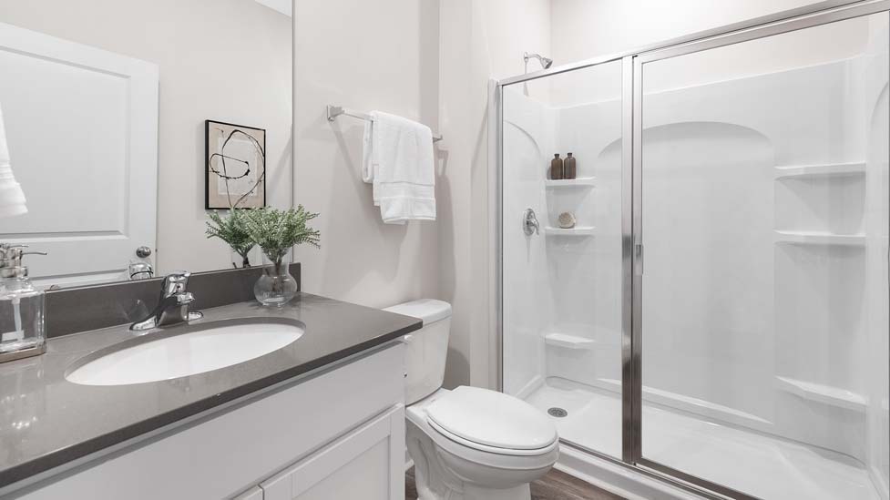 Bathroom with standing shower, white counter and cabinets