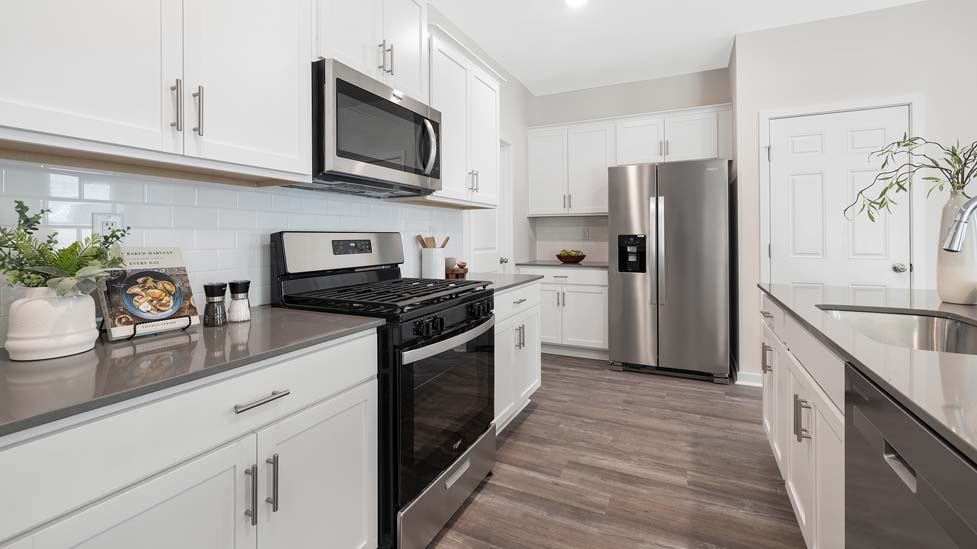 Kitchen and island with white cabinets, subway tile backsplash, and stainless steel appliances