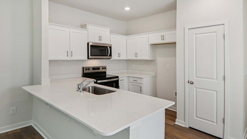 Kitchen area with white cabinets and stainless steel appliances