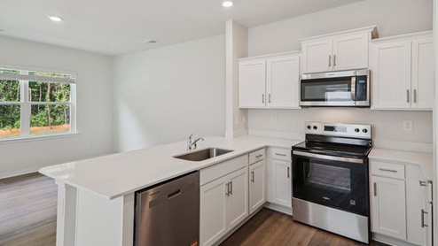 Kitchen area with white cabinets and stainless steel appliances
